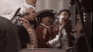 a group of people dressed in historical costumes are laughing .