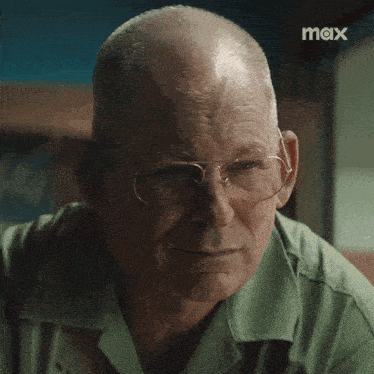 a man adjusts his glasses in front of a screen that says max