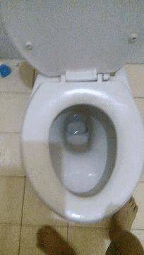 a person 's foot is standing next to a toilet with the lid open