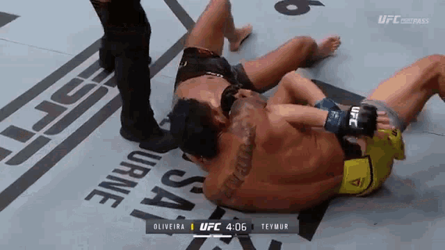 two men are wrestling on a ufc ring and one has a tattoo on his chest
