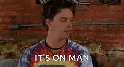 a man wearing a tie dye shirt is sitting on a couch and says `` it 's on man '' .