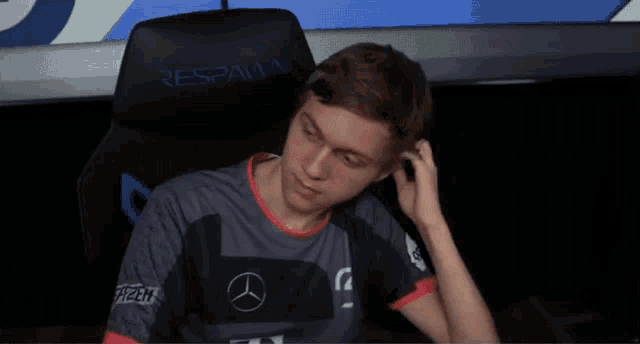 a man sitting in a chair with a mercedes logo on his sleeve
