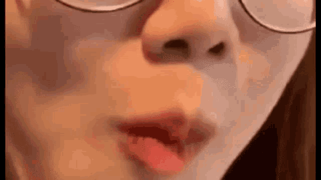 a close up of a woman 's face with glasses and red lipstick .