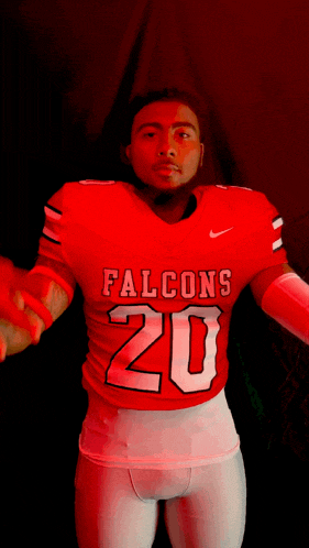 a man wearing a red falcons 20 jersey