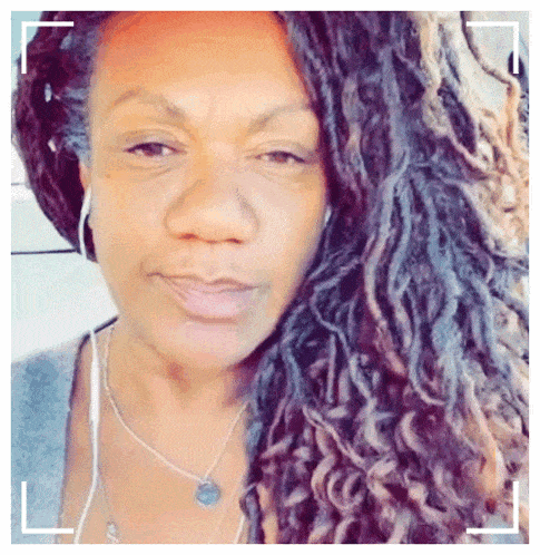 a woman with dreadlocks is wearing a necklace and ear buds
