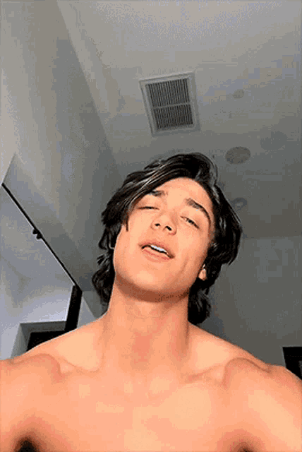 a shirtless man is taking a selfie with his eyes closed and his mouth open