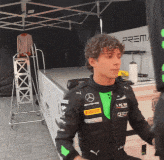 a young man in a black and green mercedes racing suit
