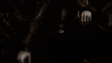a man in a suit is standing in a dark room with a blurred background .