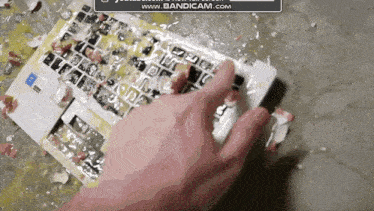 a person 's hand is reaching for a broken laptop keyboard with the words www.bandicam.com on the bottom