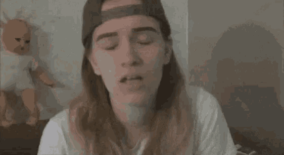 a woman with long hair is blowing smoke into her mouth while wearing a hat .