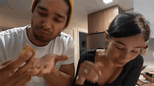 a man and a woman are eating a piece of food together