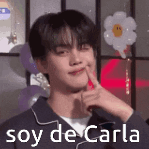 a young man is making a funny face with his finger on his chin and the words soy de carla .