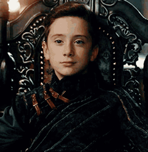 a young boy is sitting in a chair with a blanket around him