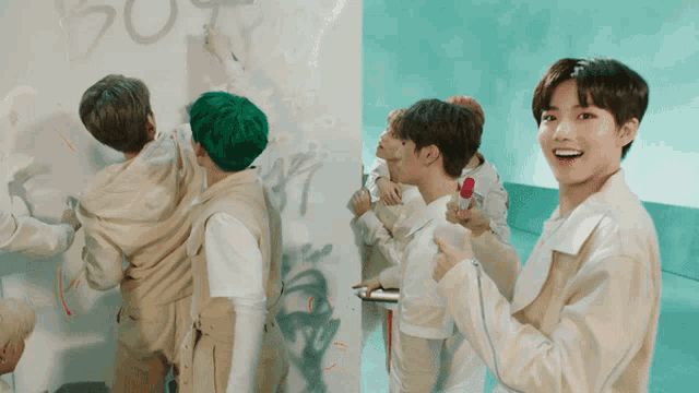 a group of young men are standing in front of a wall with graffiti on it that says " pot "