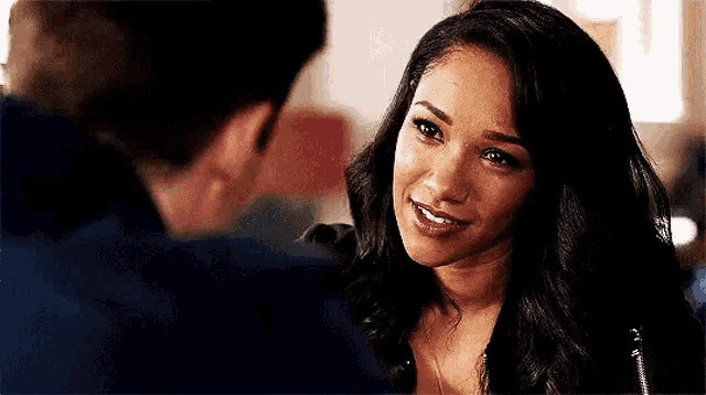 a woman is smiling while looking at a man in a blue shirt .