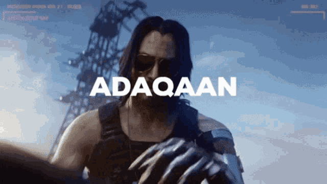 a man wearing sunglasses is standing in front of a screen that says adaqaan
