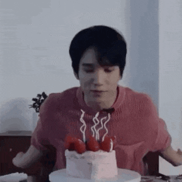 a man is sitting at a table with a cake and candles .