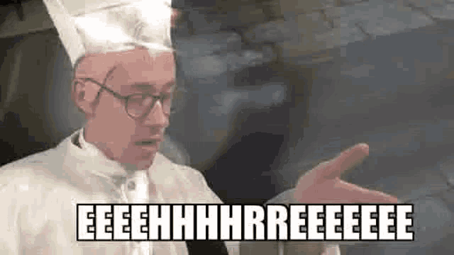 a man in a chef 's hat and glasses is making a funny face and pointing at something .