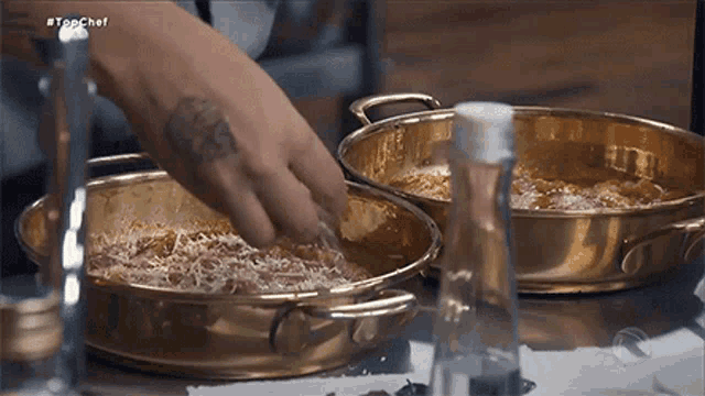 a person with a tattoo on their arm is cooking food in a pan .