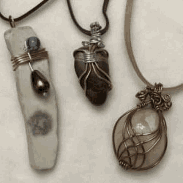 three necklaces are sitting on top of a white surface .