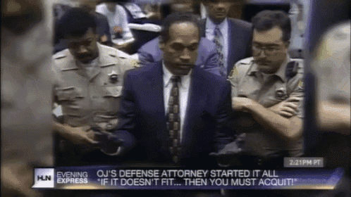 a man in a suit and tie stands in front of a group of police officers