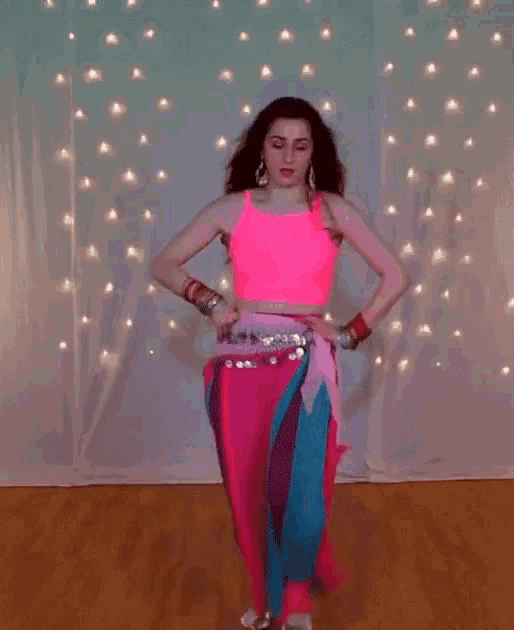 a woman is dancing in front of a white curtain with lights behind her .