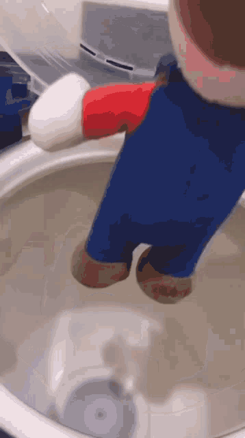 a stuffed mario character is standing in a toilet