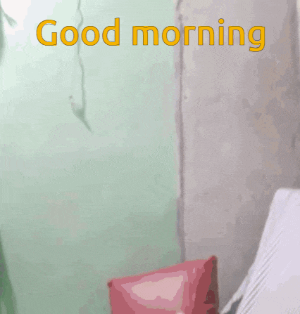 a man is smiling in front of a green wall with the words good morning on it