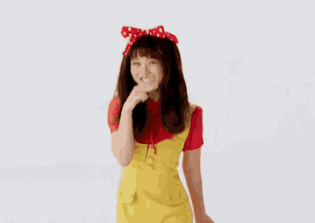 a woman in a yellow dress and red shirt is blowing a kiss while wearing a red headband .