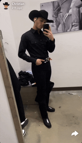 a man in a cowboy hat takes a selfie in front of a mirror