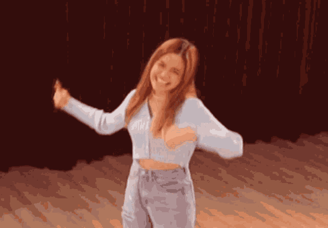 a woman in a blue sweater and jeans is dancing
