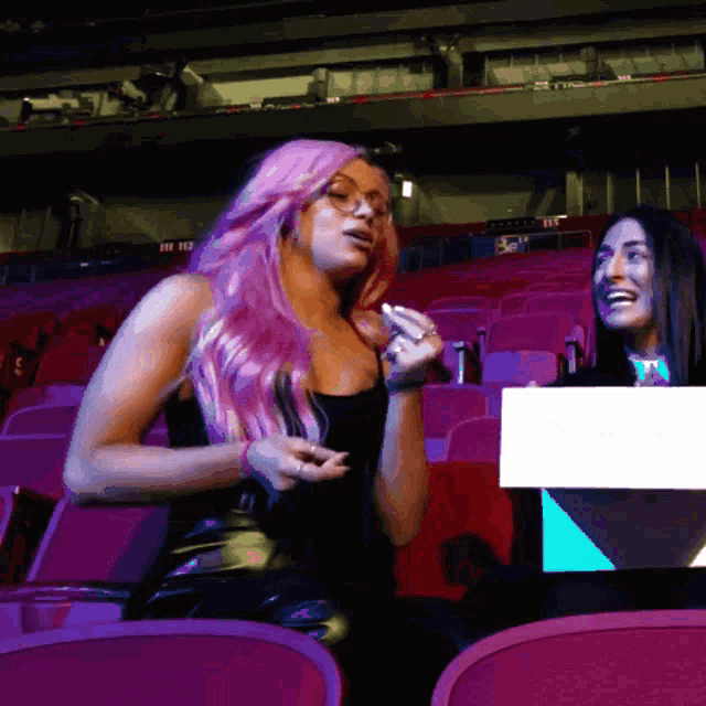 a woman with pink hair sits in a stadium with a sign that says ' ii ' on it