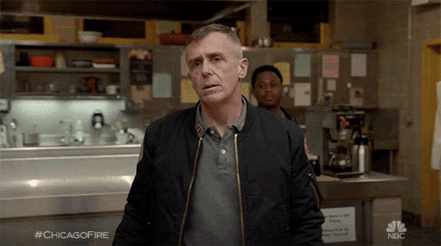 a man in a bomber jacket is standing in a kitchen with #chicagofire on the bottom
