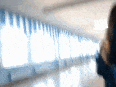 a blurry picture of a person walking down a hallway with blue curtains