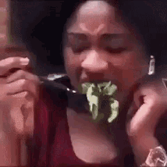 a woman is eating a piece of lettuce with a fork in her mouth .
