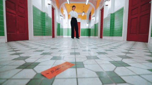 a person standing in a hallway with a note on the floor that says ' deli '