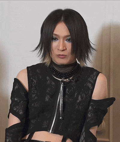 a woman wearing a choker and a crop top is looking at the camera