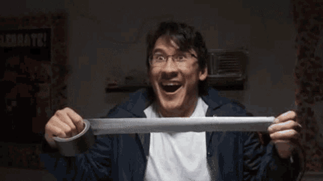 a man in a suit is holding a large knife in his hand and smiling .