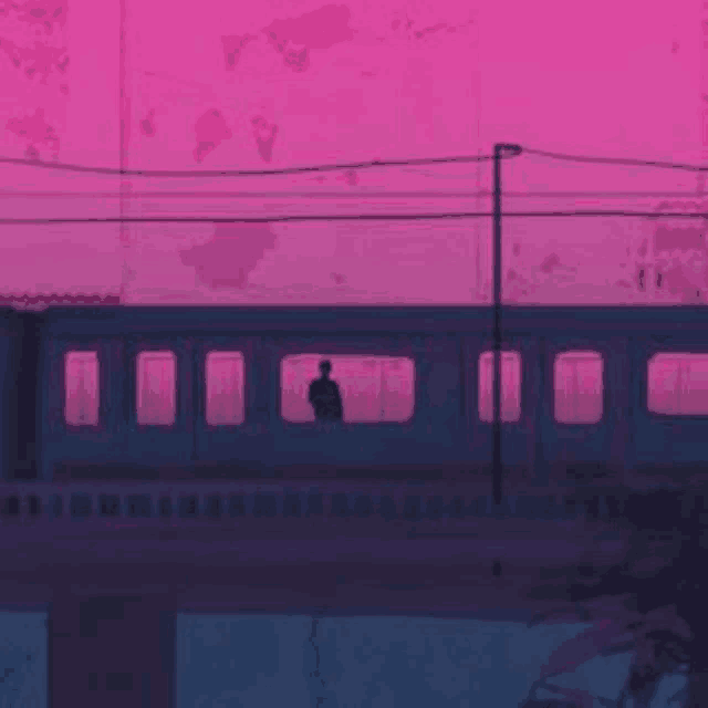 a man is standing on a train platform at sunset .