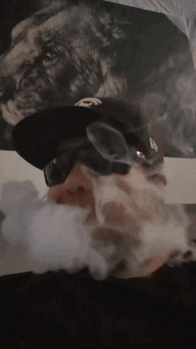 a man wearing a hat with the letter e on it is smoking a cigarette