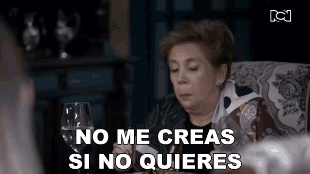 a woman is sitting at a table with a glass of wine and the words no me creas si no quieres