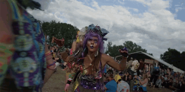 a woman with purple hair and a cat face is dancing in front of a crowd