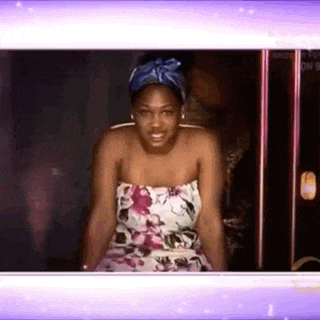 a woman in a strapless floral dress is standing in front of a purple background .