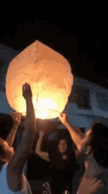 a group of people are holding a lantern in the air