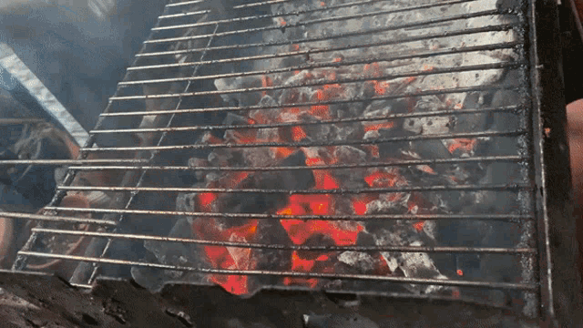 a grill with a lot of coals on it and smoke coming out of it