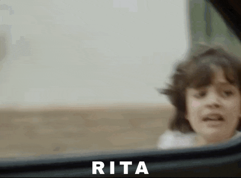 a little girl is looking out the window of a car and making a funny face .