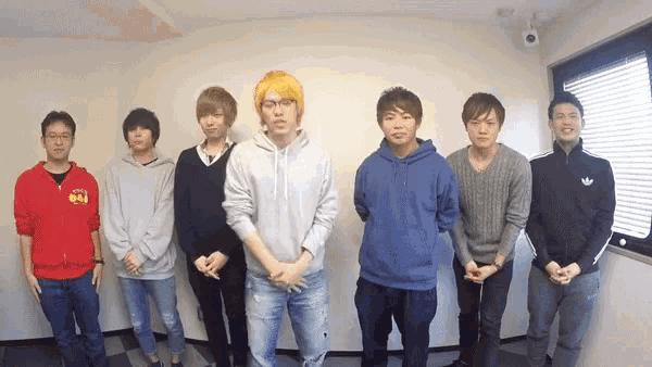 a group of young men standing in a room with one wearing a red jacket that says ' tokyo '