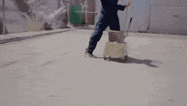 a man is pushing a cart with a mop and a box on it .