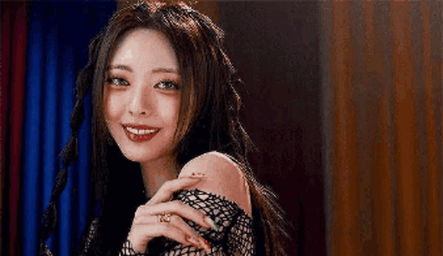 a close up of a woman wearing a fishnet top and smiling at the camera .