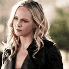 a woman with blonde hair is wearing a black jacket and a red top .